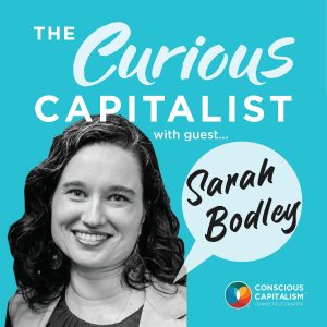 The Curious Capitalist podcast cover with Sarah Bodley. Sarah is a white woman with dark curly hair, wearing a blouse and blazer.